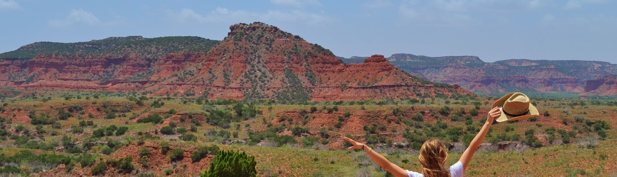 Canyon and girl standing, raising her arm.s